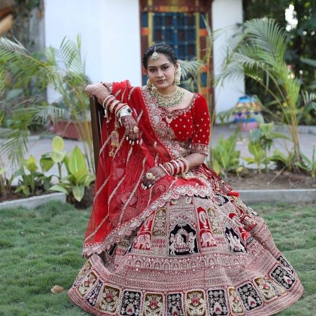 Traditional Indian bride in a red lehenga with intricate gold embroidery, styled with elegant bridal makeup and jewelry